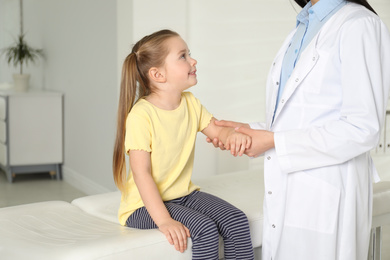 Photo of Professional orthopedist examining little patient's arm in clinic