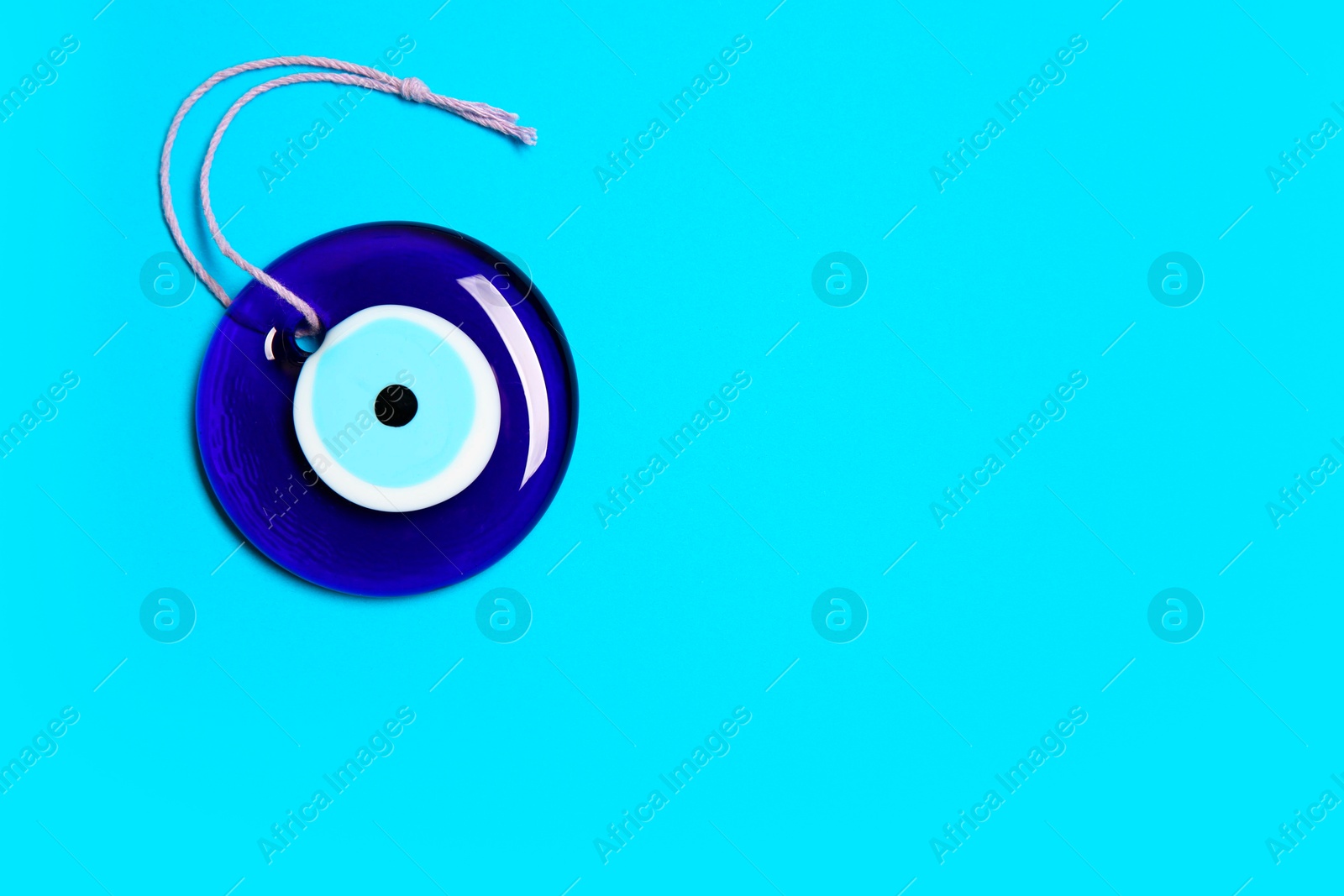 Photo of Evil eye amulet on light blue background, top view. Space for text