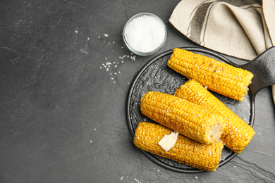 Photo of Delicious grilled corn served on dark table, flat lay. Space for text