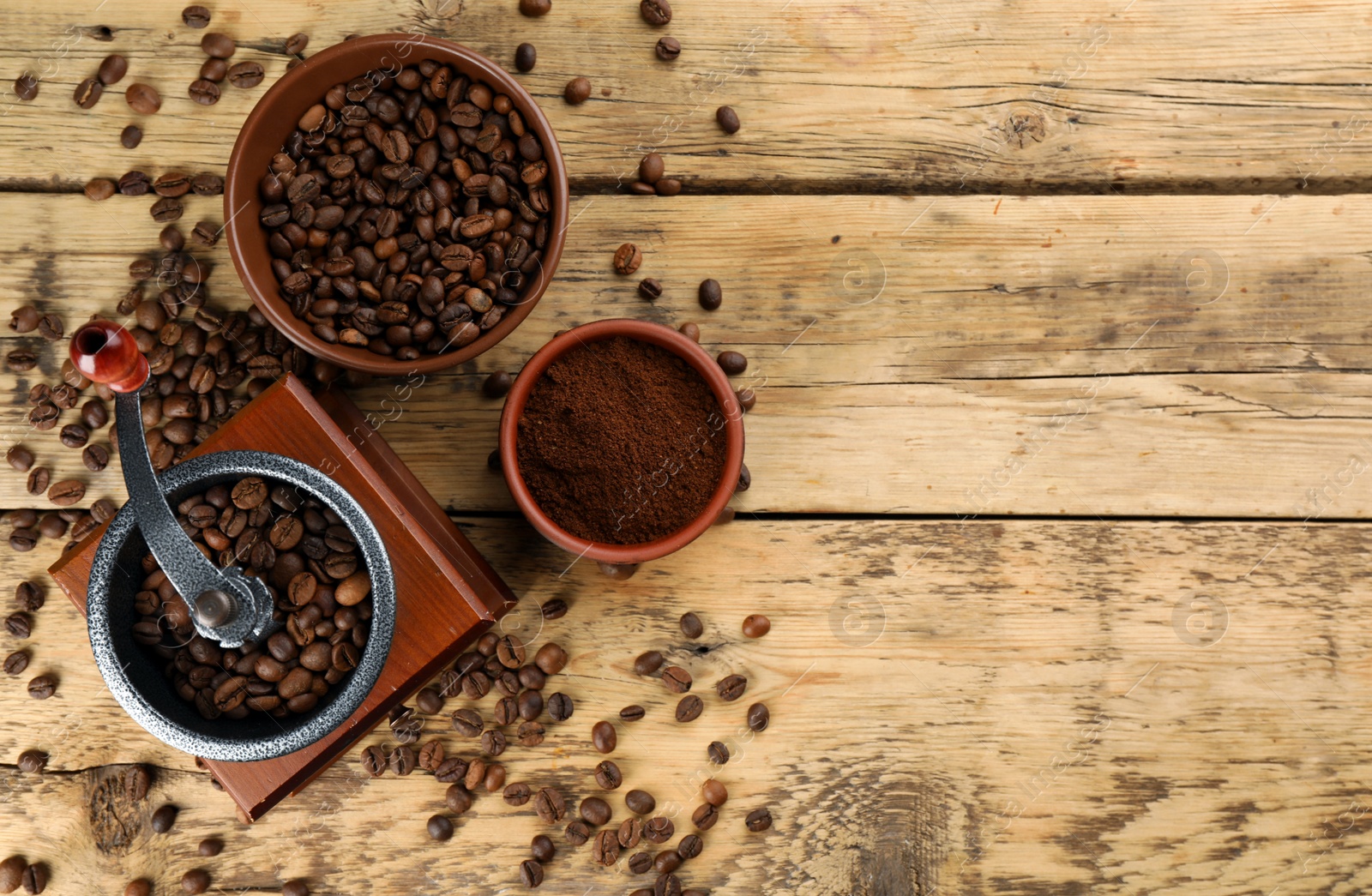 Photo of Vintage manual coffee grinder with beans and powder on wooden table, flat lay. Space for text