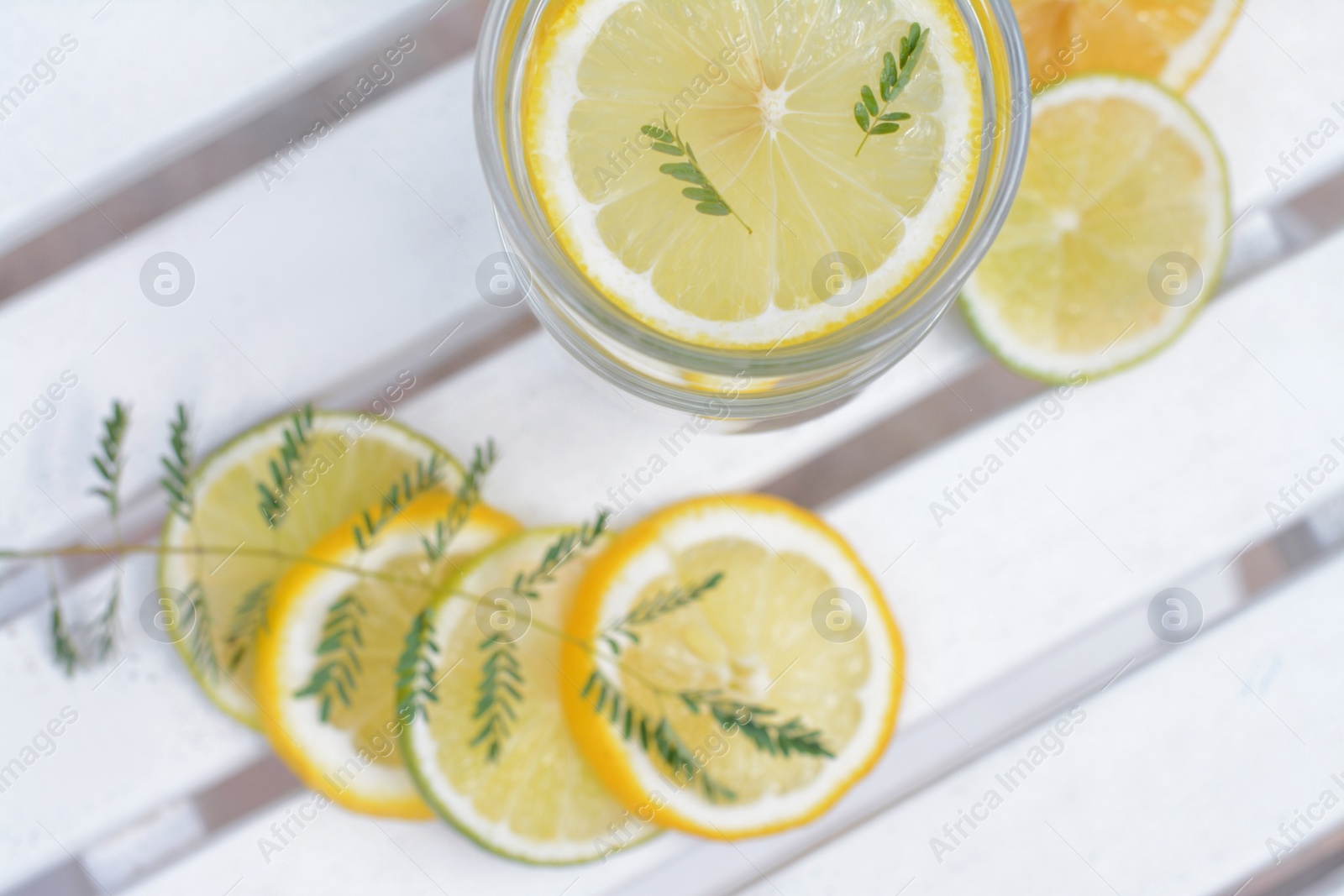 Photo of Delicious refreshing lemonade and pieces of citrus on white wooden table outdoors, flat lay