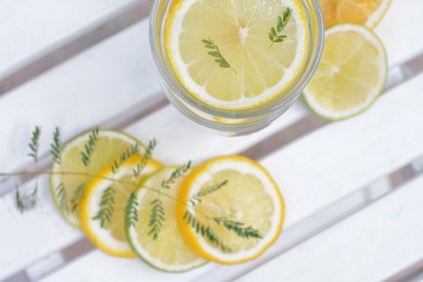Delicious refreshing lemonade and pieces of citrus on white wooden table outdoors, flat lay