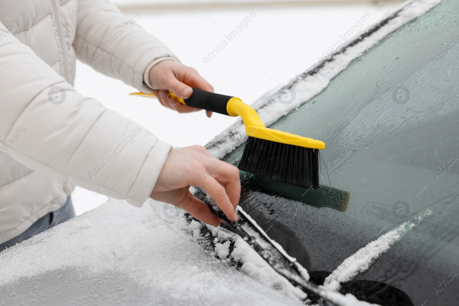 Photo of Man cleaning snow from car windshield outdoors, closeup