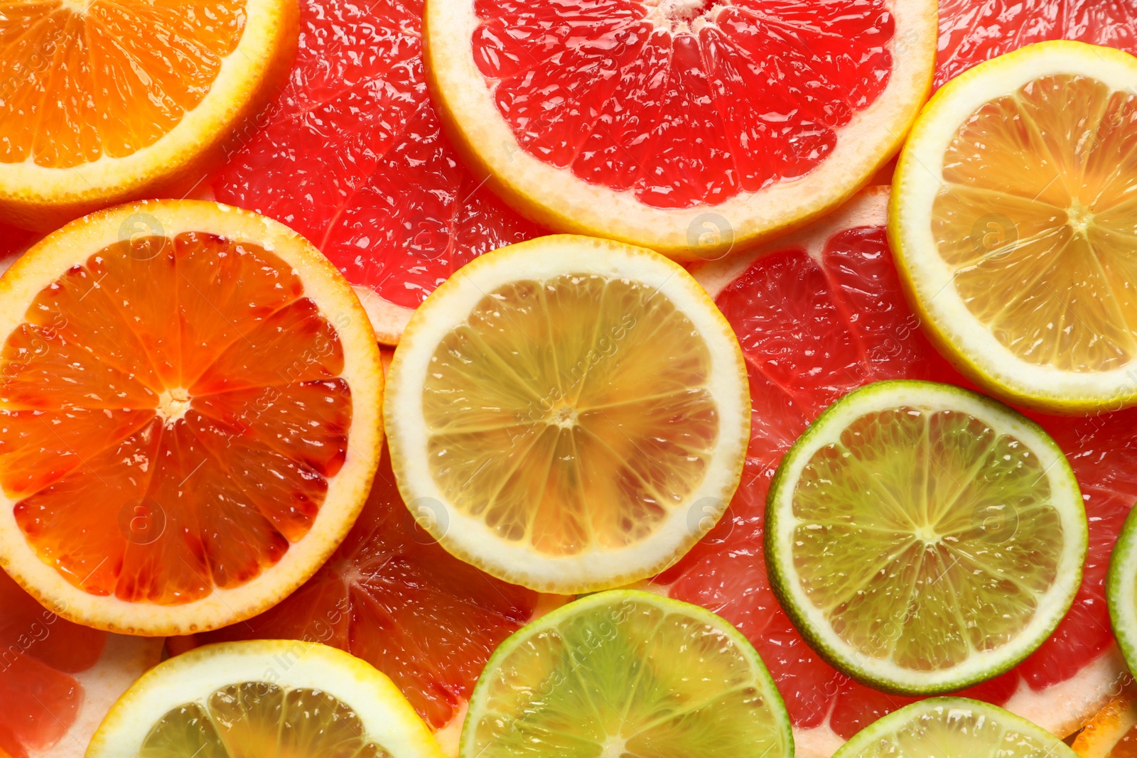 Photo of Slices of fresh citrus fruits as background, top view