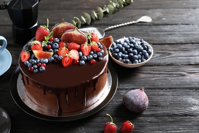 Photo of Fresh delicious homemade chocolate cake with berries on dark table