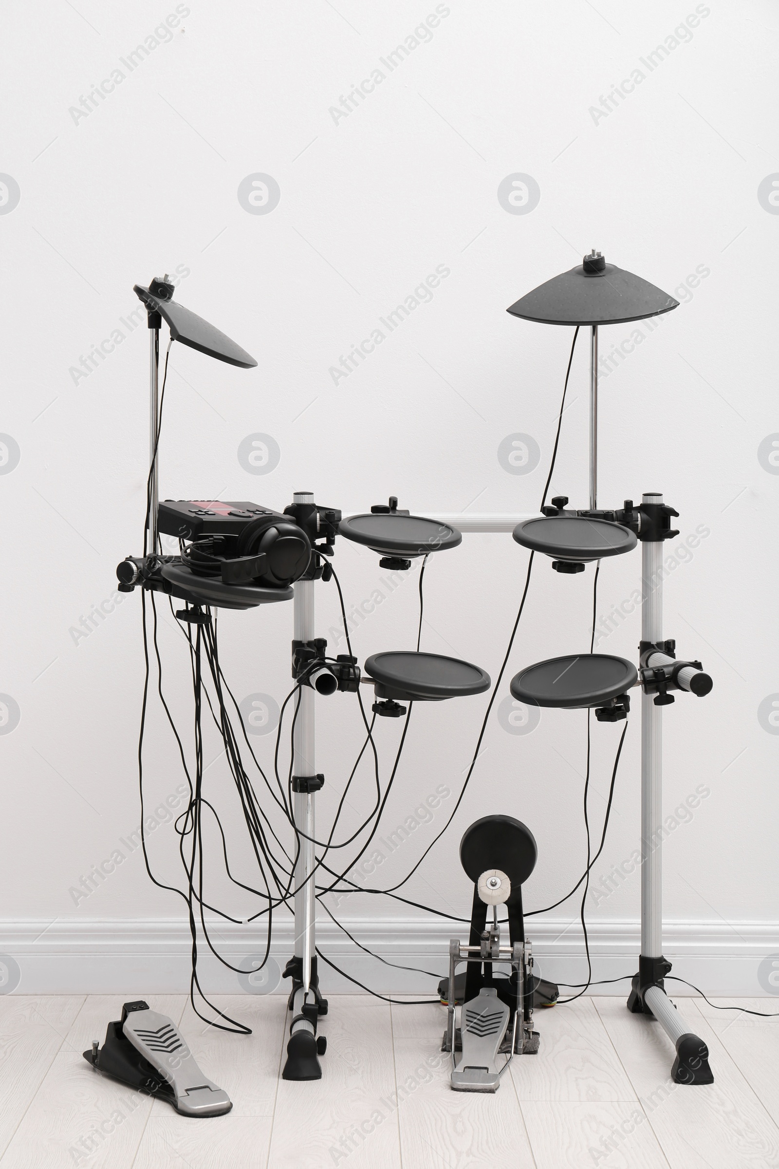 Photo of Modern electronic drum kit near white wall indoors. Musical instrument
