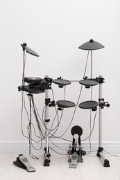 Modern electronic drum kit near white wall indoors. Musical instrument