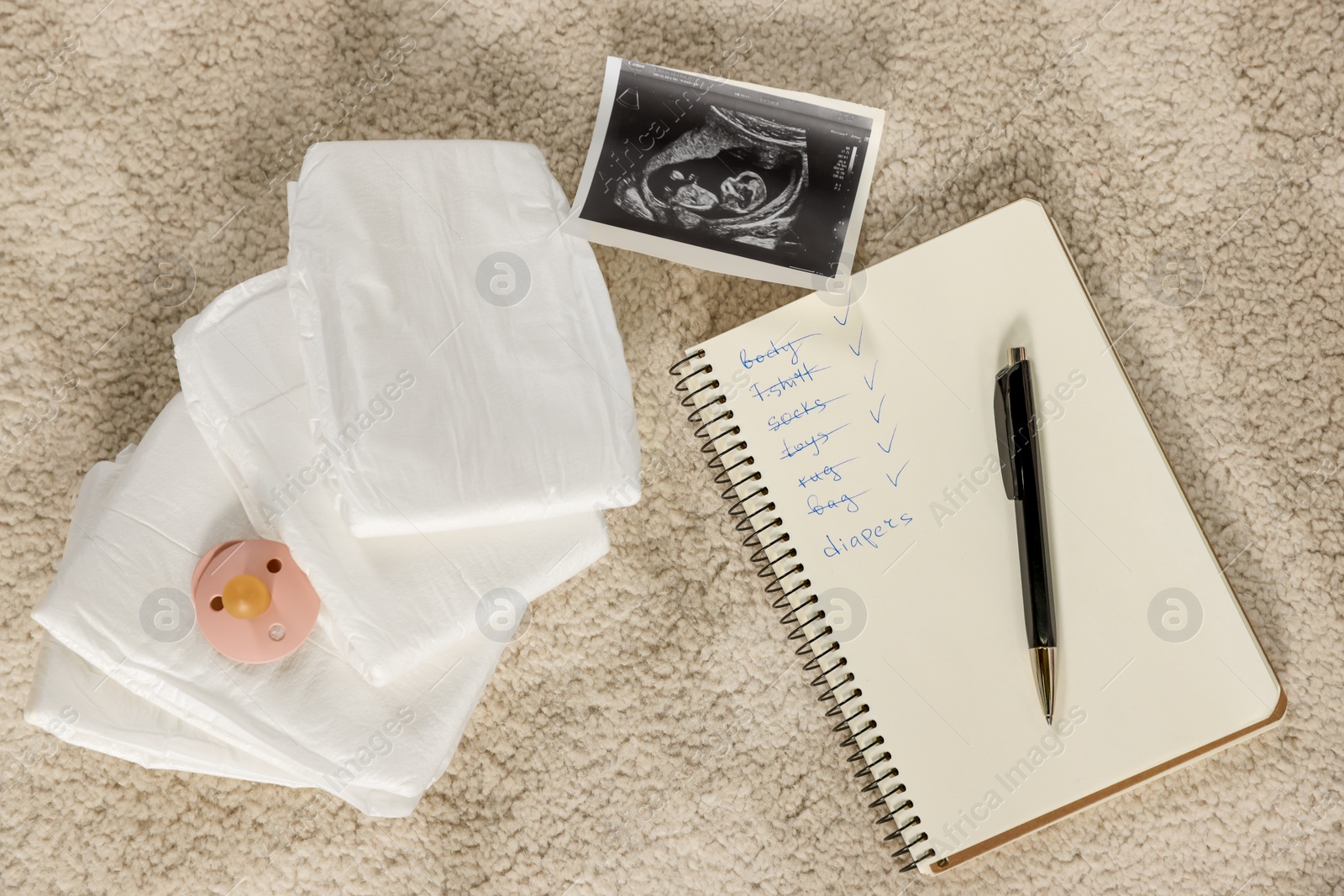 Photo of Flat lay composition with baby stuff, list and ultrasound scan on beige carpet