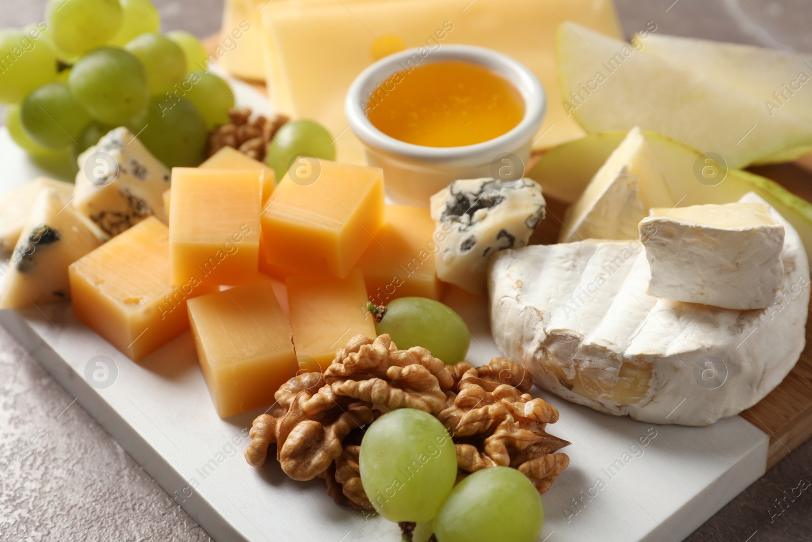 Photo of Board with different kinds of delicious cheese and snacks on table, closeup