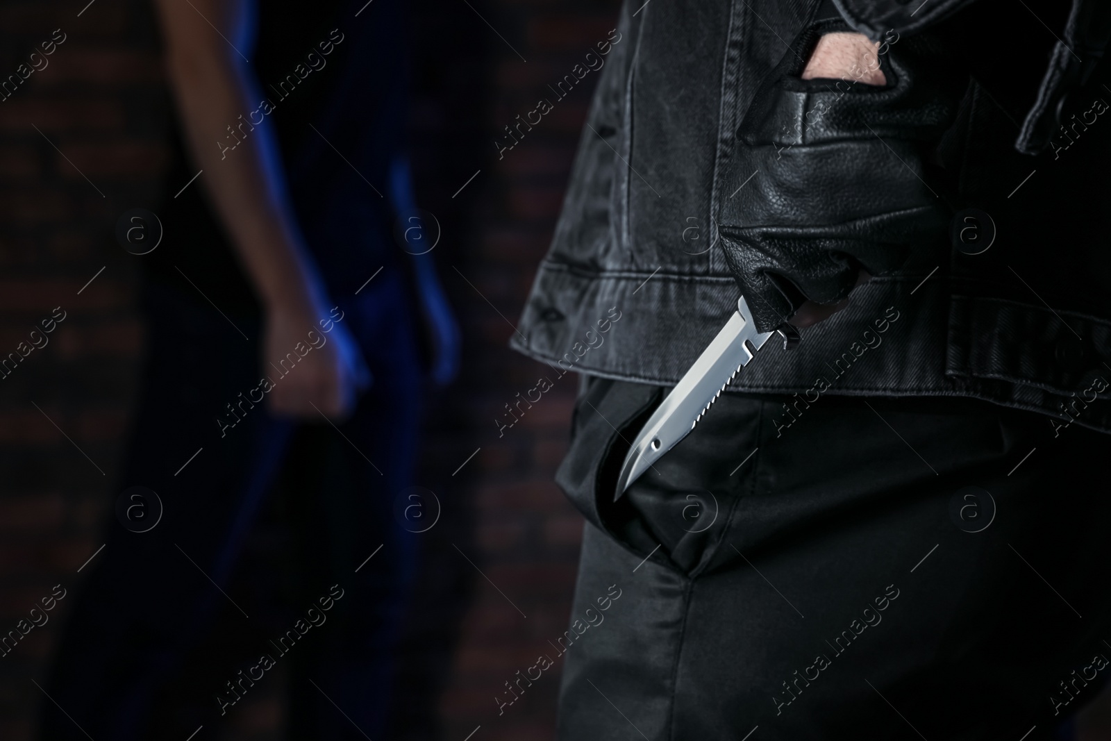 Photo of Man with knife behind his back and victim indoors, closeup. Dangerous criminal