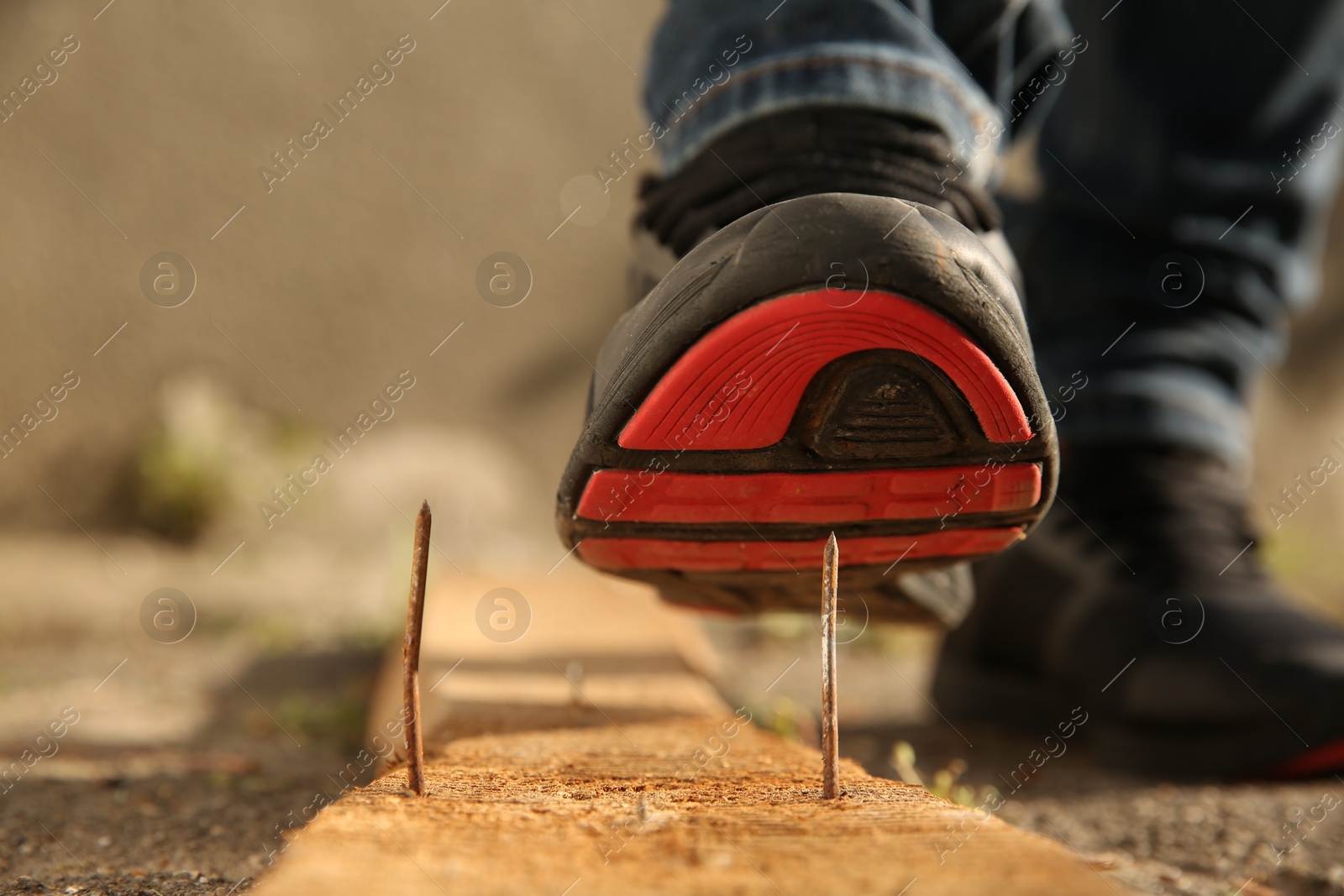 Photo of Careless worker stepping on nail in wooden plank outdoors, closeup