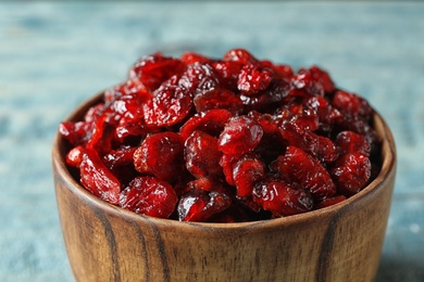 Photo of Wooden bowl with cranberries on table, closeup. Dried fruit as healthy snack