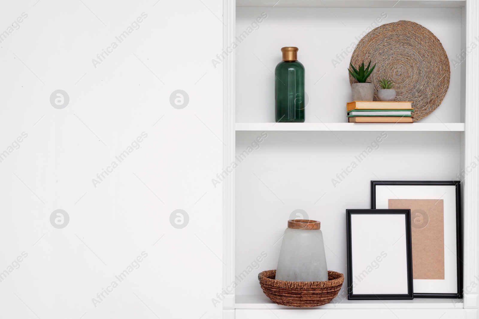 Photo of Shelves with different decor near beige wall, space for text. Interior design