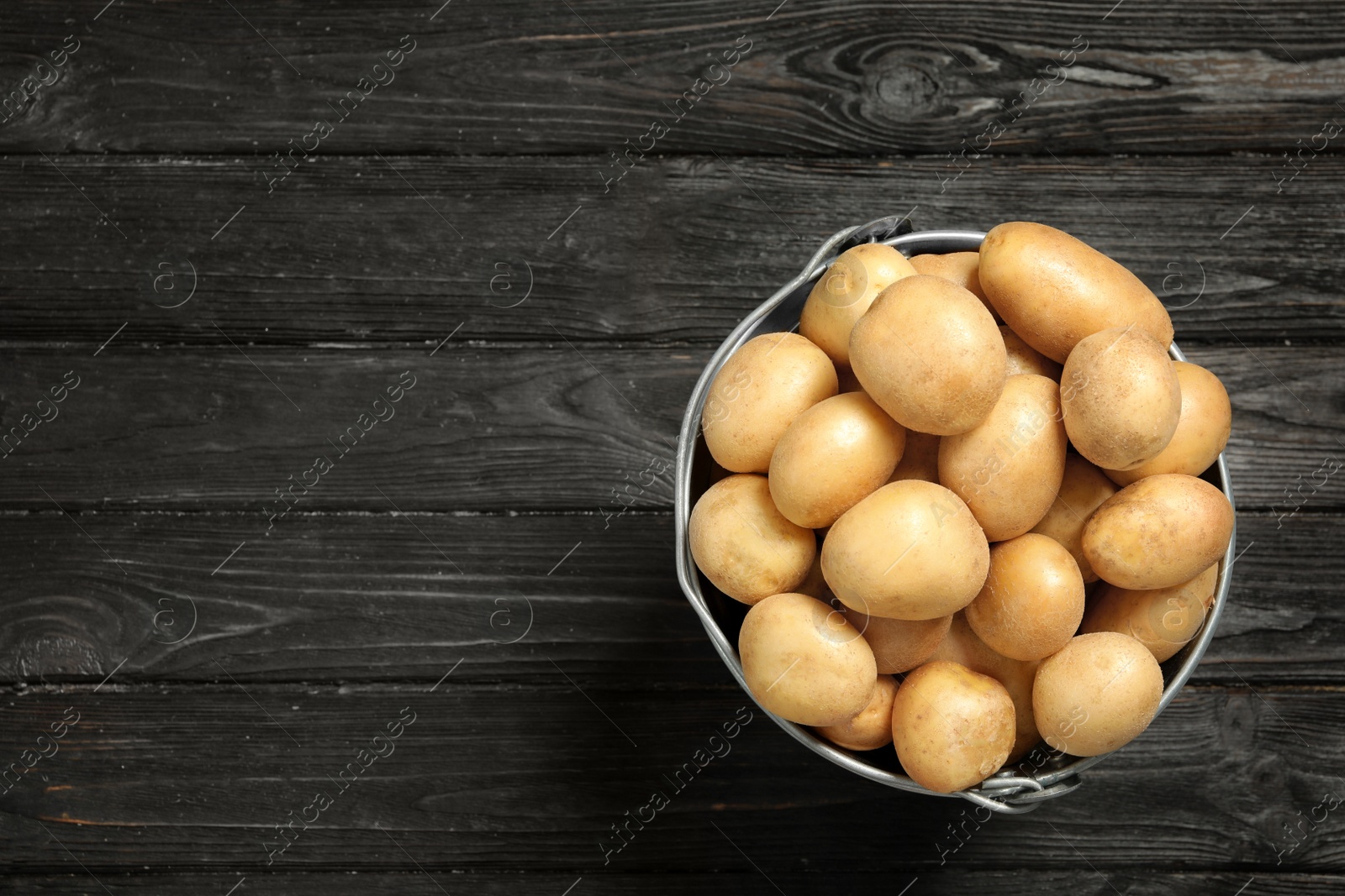 Photo of Raw fresh organic potatoes on black wooden background, top view. Space for text