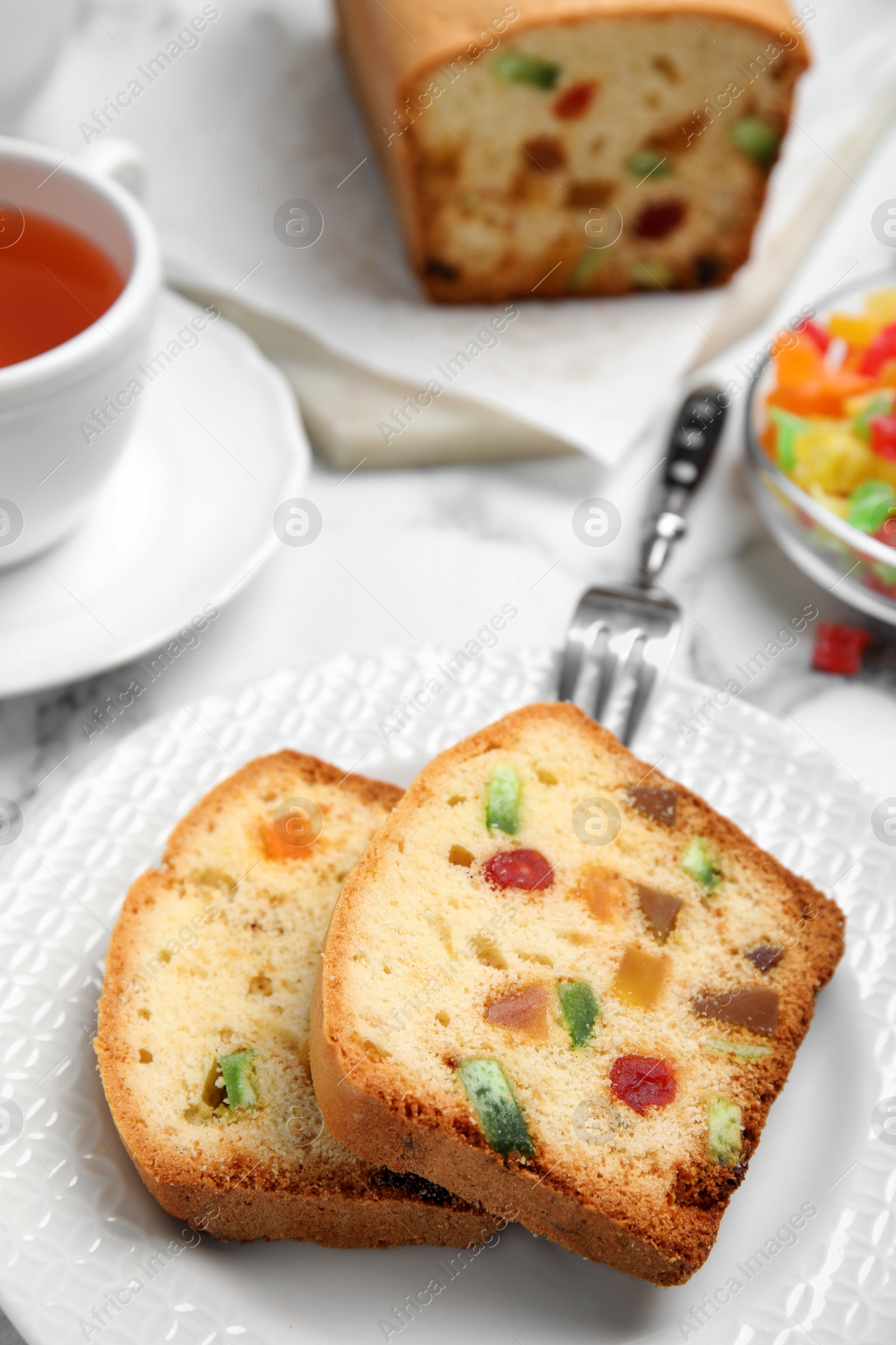 Photo of Delicious cake with candied fruits and tea on table, closeup