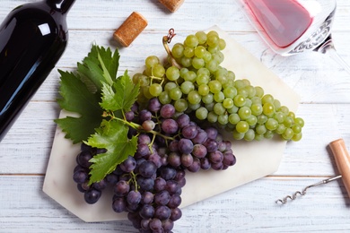 Flat lay composition with fresh ripe juicy grapes and wine on white wooden table