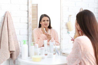 Photo of Young woman with sensitive teeth in bathroom