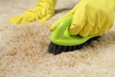 Photo of Woman removing stain from beige carpet, closeup