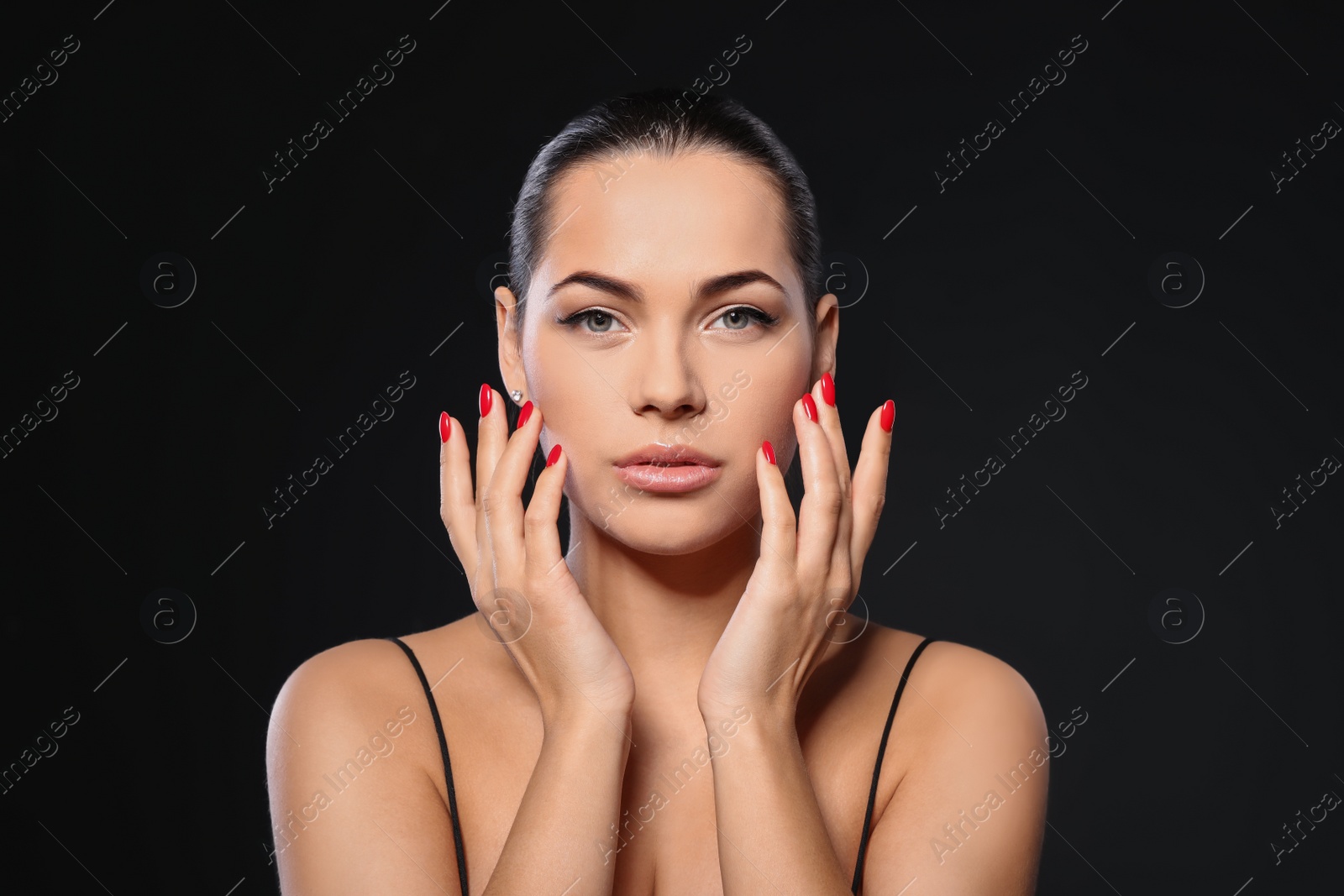 Photo of Portrait of beautiful young woman with bright manicure on black background. Nail polish trends