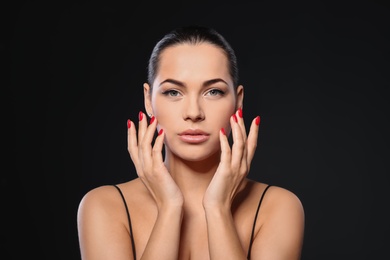 Portrait of beautiful young woman with bright manicure on black background. Nail polish trends