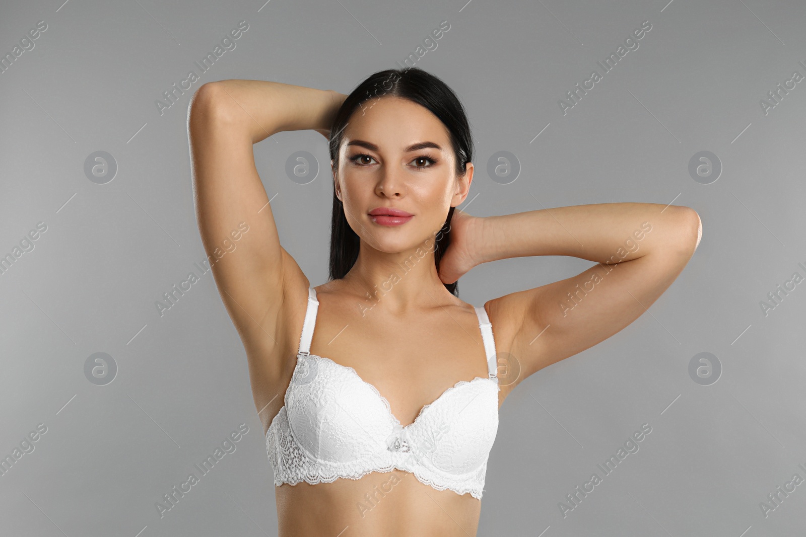 Photo of Beautiful young woman in white underwear on grey background