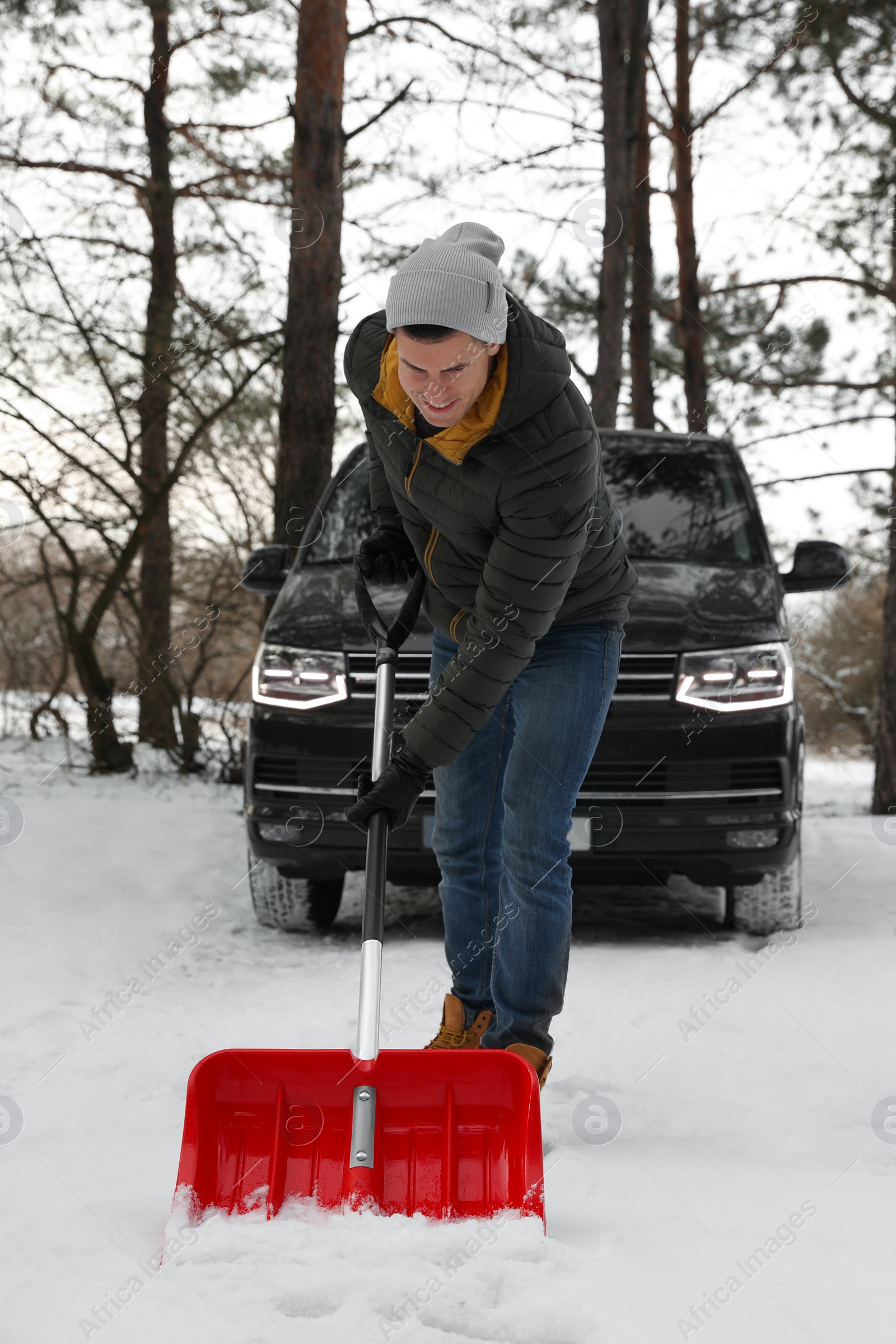 Photo of Man removing snow with shovel near car outdoors on winter day