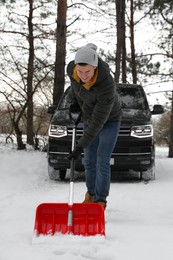 Man removing snow with shovel near car outdoors on winter day