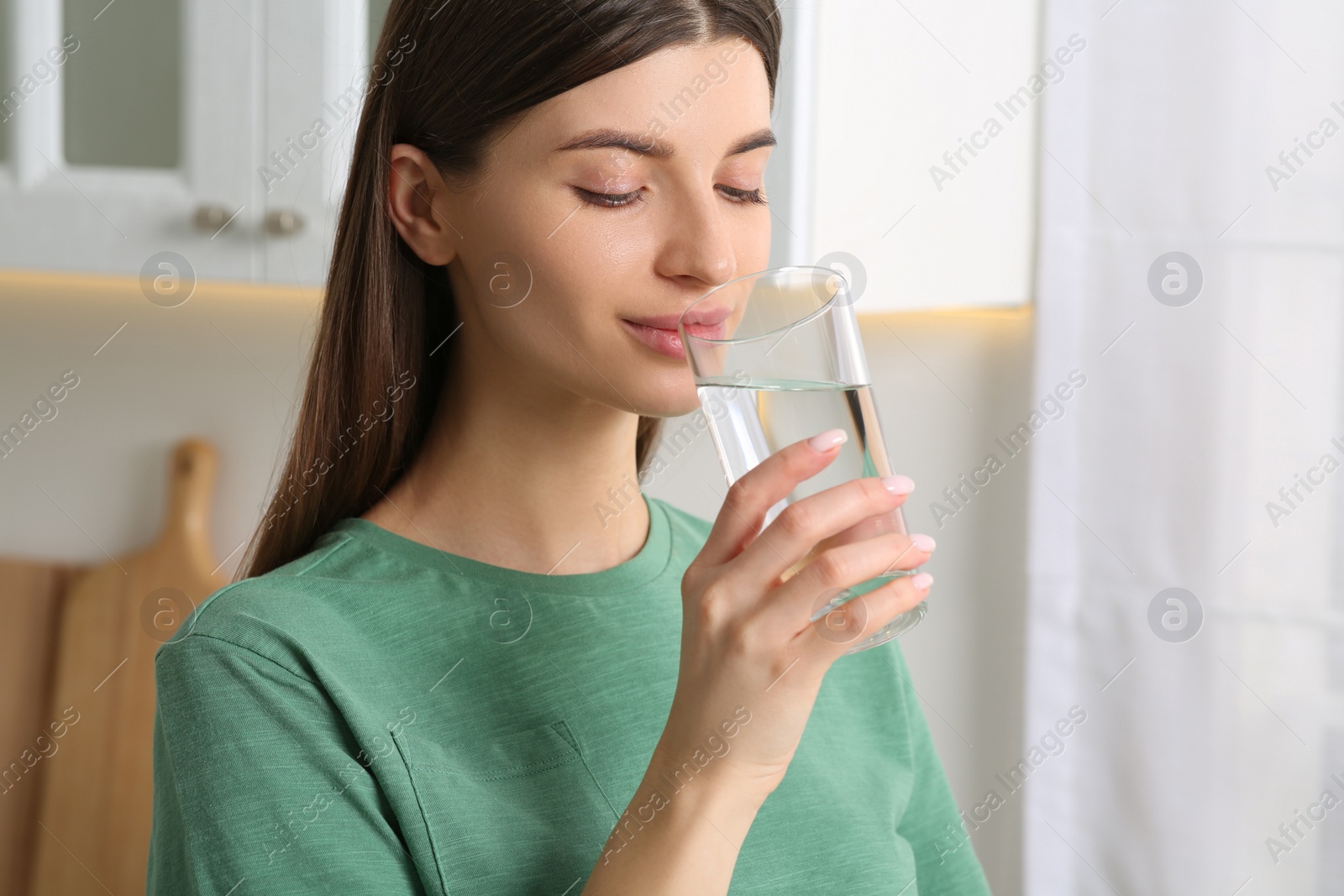 Photo of Healthy habit. Woman drinking fresh water from glass indoors