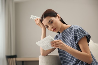 Confused young woman with pills reading medicine instruction at home