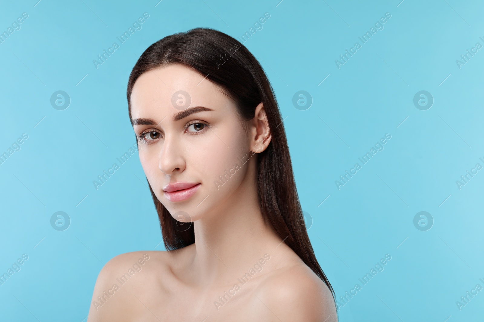 Photo of Portrait of beautiful young woman on light blue background. Space for text