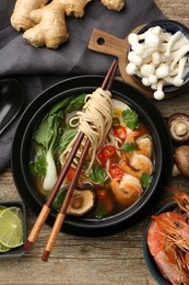Photo of Flat lay composition with delicious ramen in bowl and ingredients on wooden table. Noodle soup