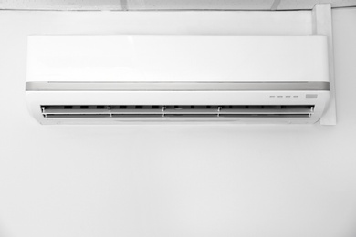 Photo of Modern air conditioner on white wall indoors