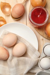 Easter eggs painted with natural food coloring and onions on wooden table, flat lay