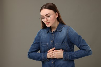 Photo of Woman suffering from stomach pain on grey background