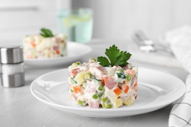 Photo of Delicious salad Olivier in plate on light table