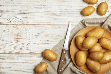 Photo of Fresh ripe organic potatoes on wooden background, top view