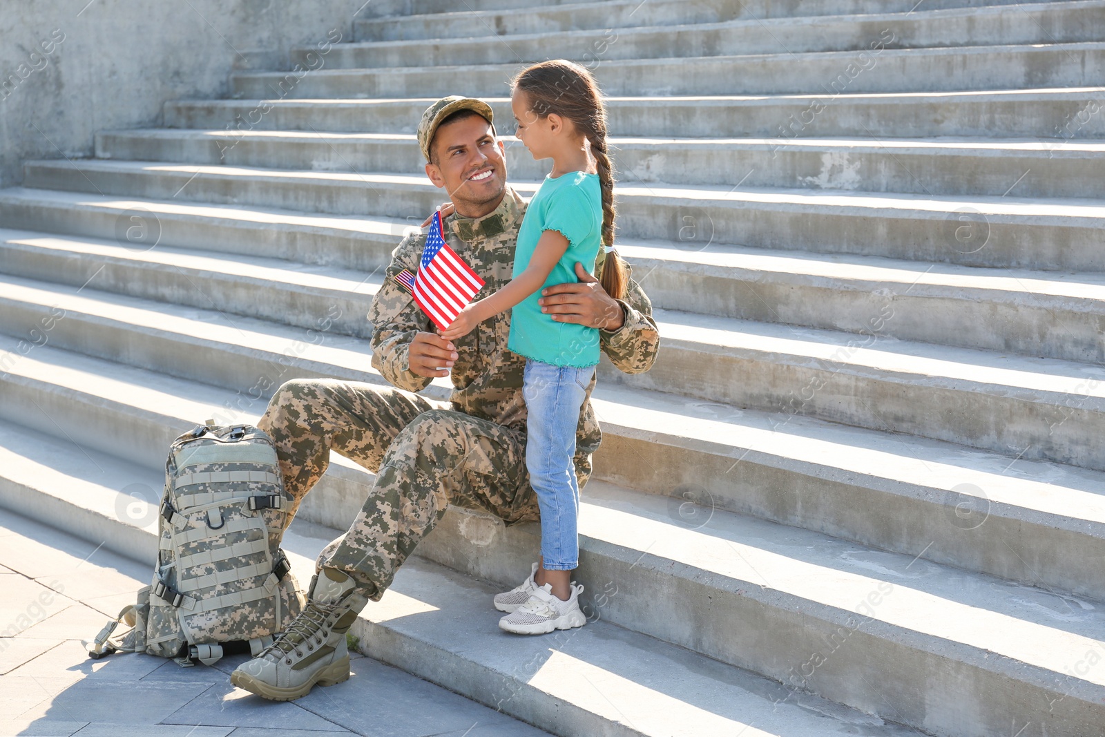 Photo of Soldier and his little daughter with flag of USA outdoors, space for text