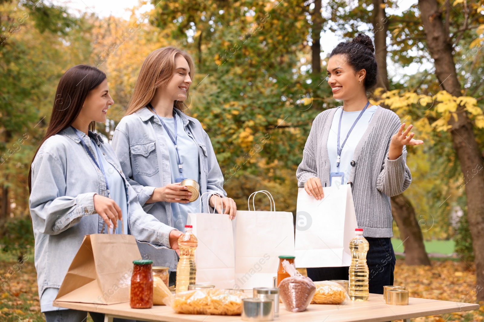 Photo of Group of volunteers packing food products at table in park