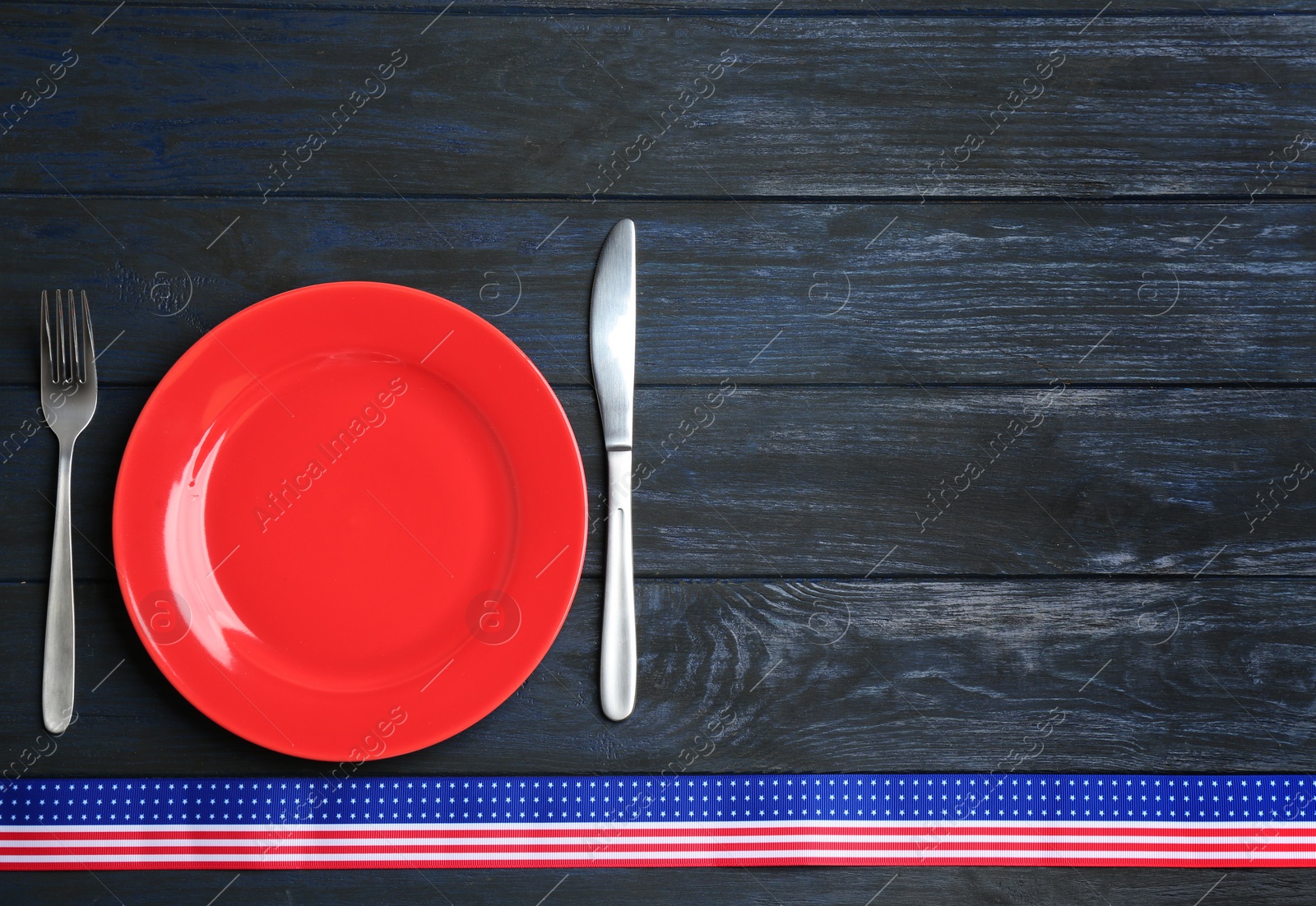 Photo of Patriotic table setting with traditional USA colors on wooden background, flat lay. Space for text