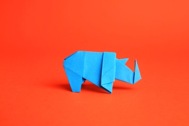 Photo of Origami art. Handmade light blue paper rhinoceros on orange background