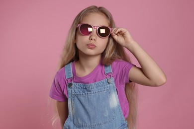 Girl in stylish sunglasses on pink background