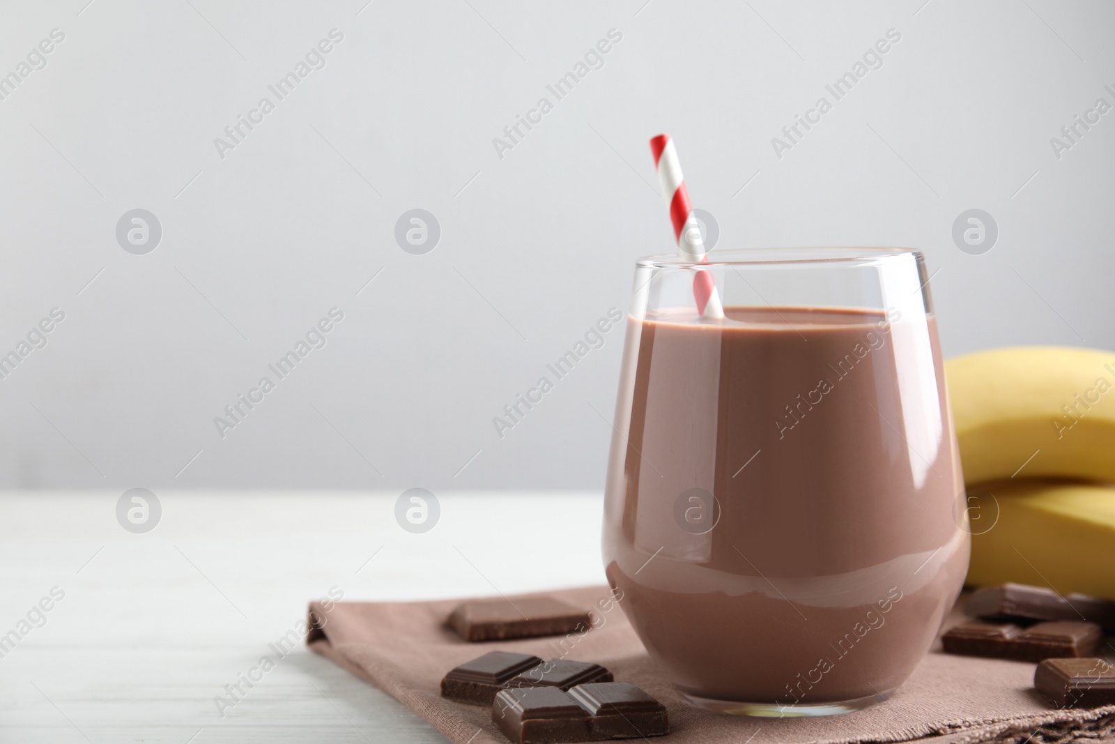 Photo of Fresh yummy chocolate milk on white wooden table. Space for text