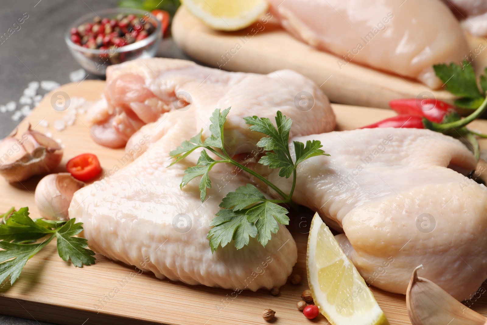 Photo of Fresh raw chicken wings and other products on wooden board, closeup