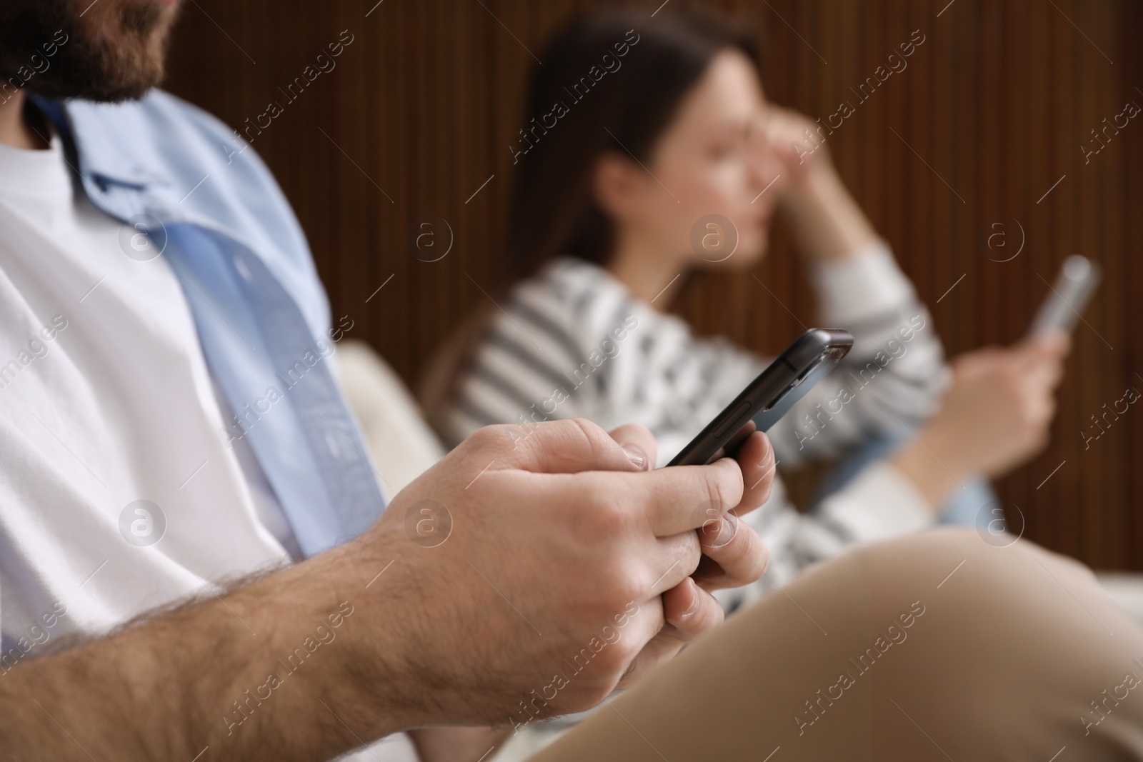 Photo of Couple addicted to smartphones at home, closeup. Relationship problems