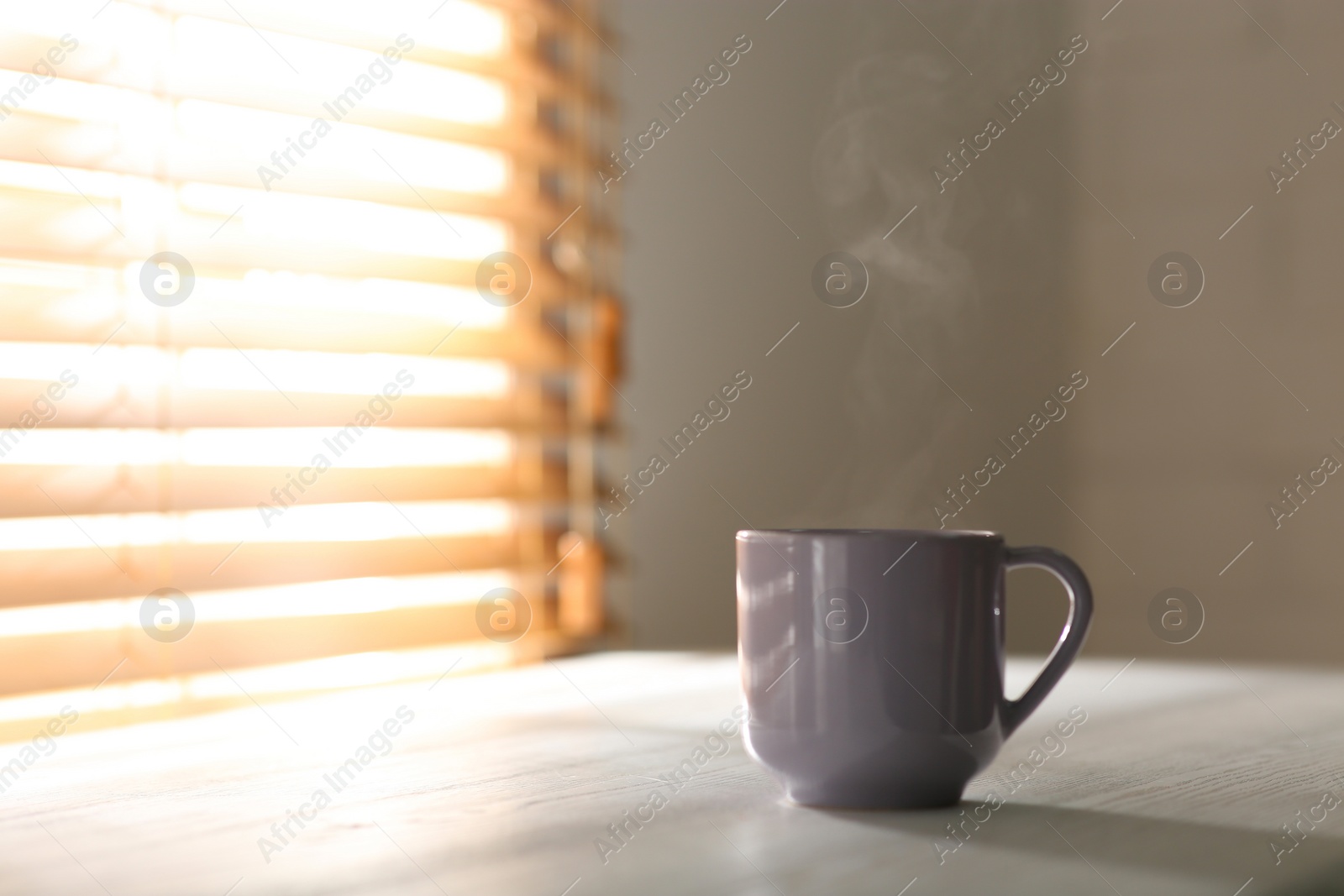 Photo of Cup of delicious coffee on white wooden table, space for text. Good morning