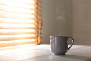 Photo of Cup of delicious coffee on white wooden table, space for text. Good morning