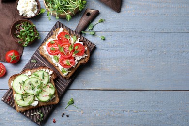 Photo of Delicious sandwiches with vegetables, cheese and microgreens on grey wooden table, flat lay. Space for text