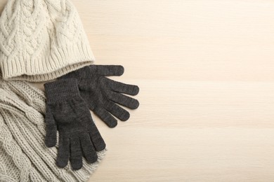 Photo of Stylish gloves, scarf and hat on white wooden background, flat lay. Space for text