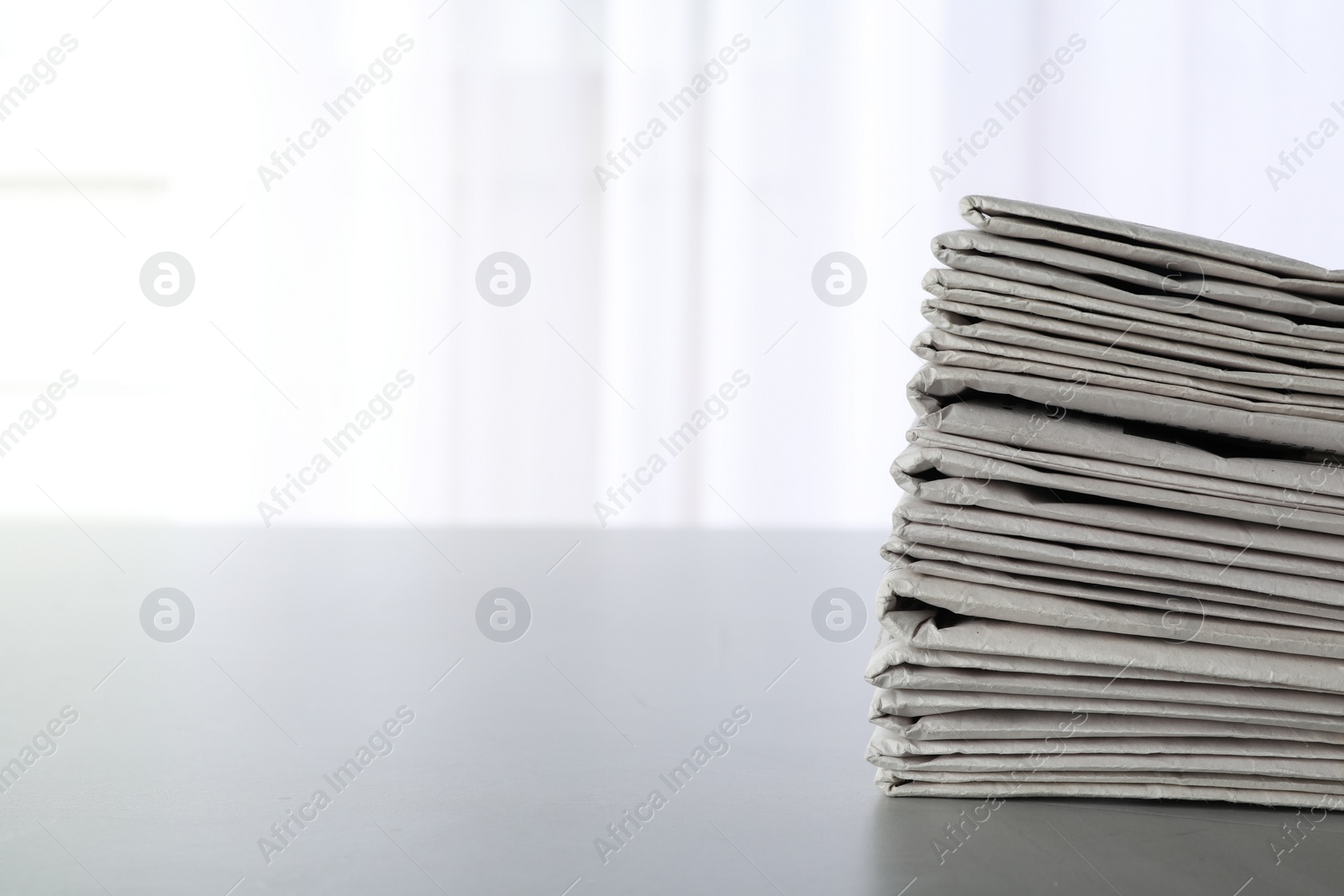 Photo of Stack of newspapers on grey table, space for text. Journalist's work