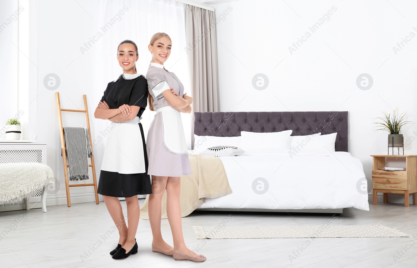 Image of Beautiful chambermaids near bed in hotel room